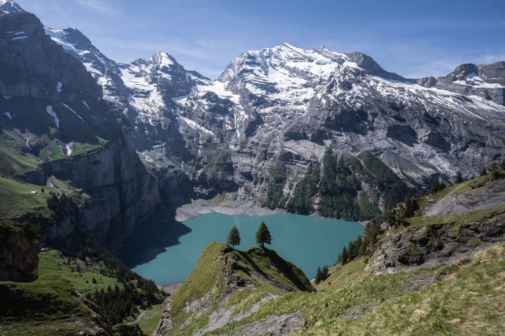 The Oeschinensee hike view from the trail over the turquoise waters of the lake and the surrounding cliffs, one of the very best hiking and photography locations in Switzerland.