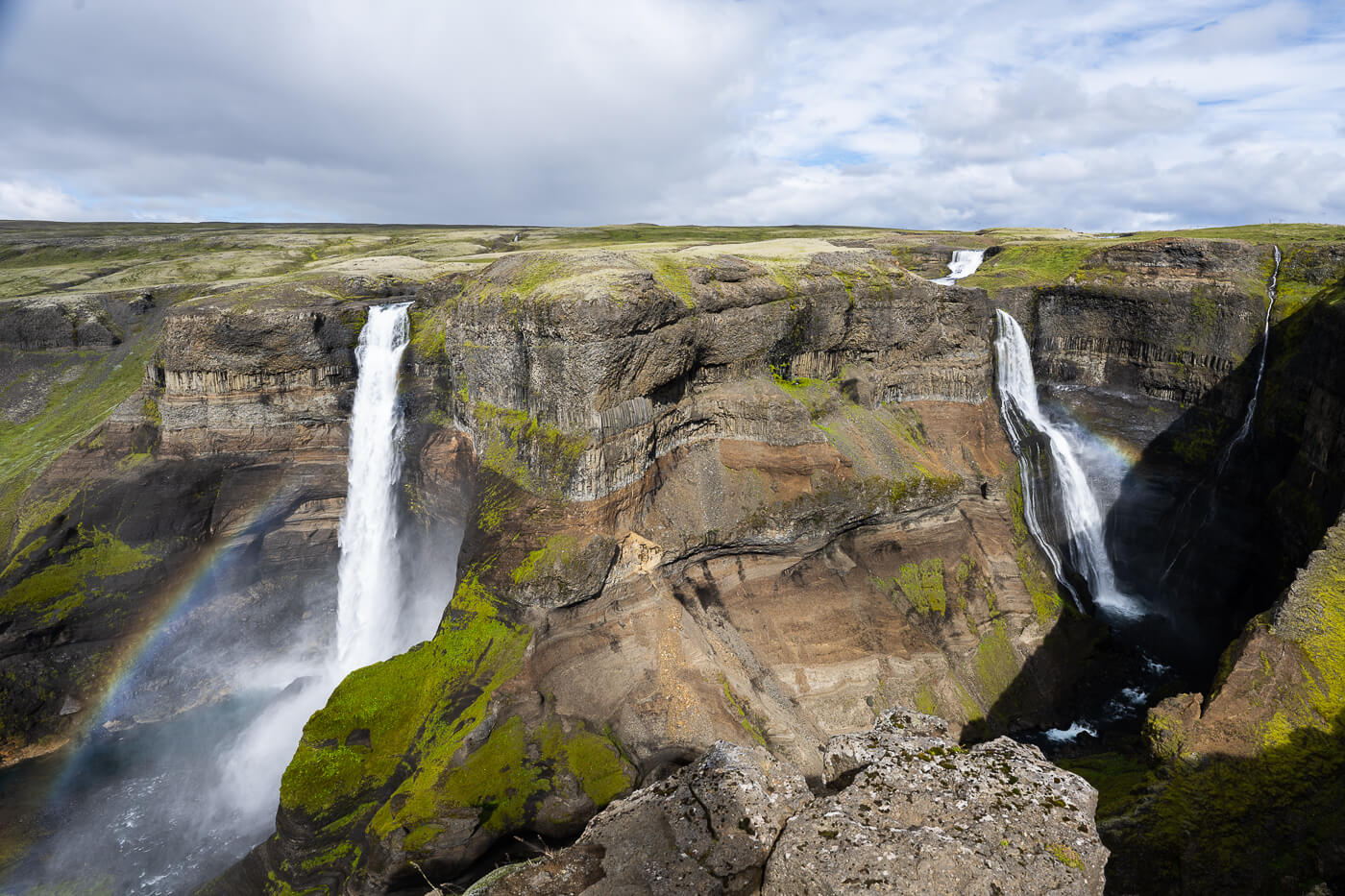 spectacular view of the twin waterfalls Haifoss and Granni lit by the sun, with a rainbow which creates a unique scene.