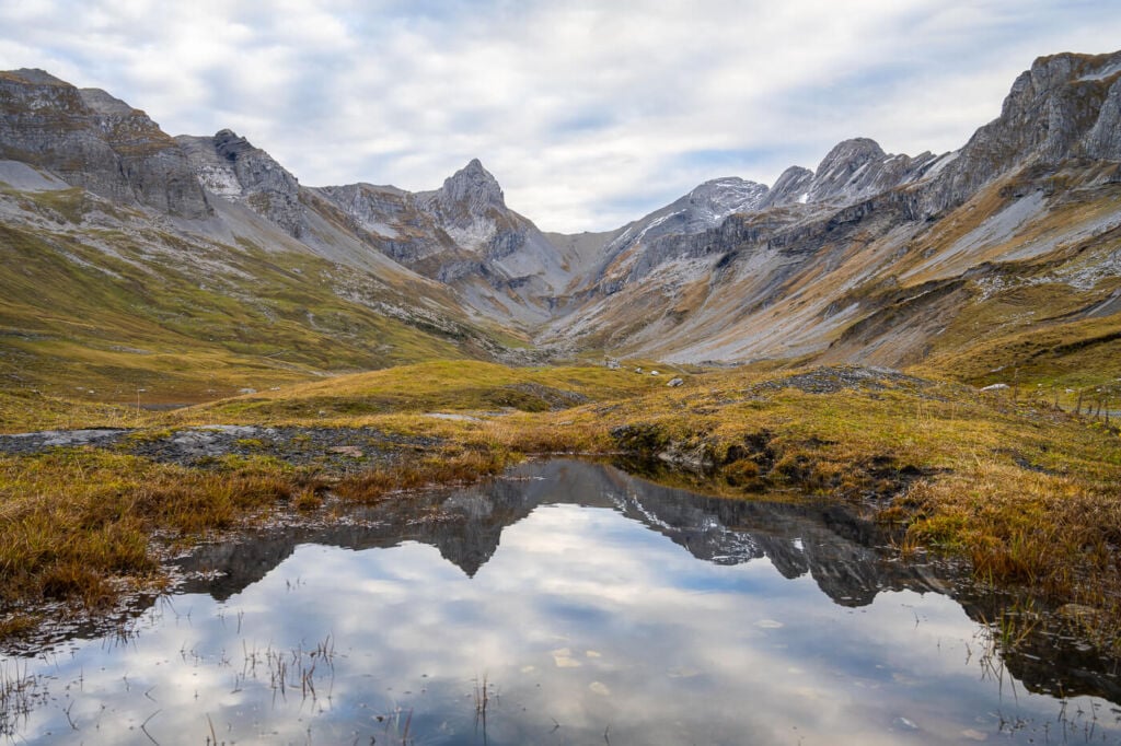 Hiking to ortstock and glattalp, alpine landscape reflected in the waters of a still alpine lake