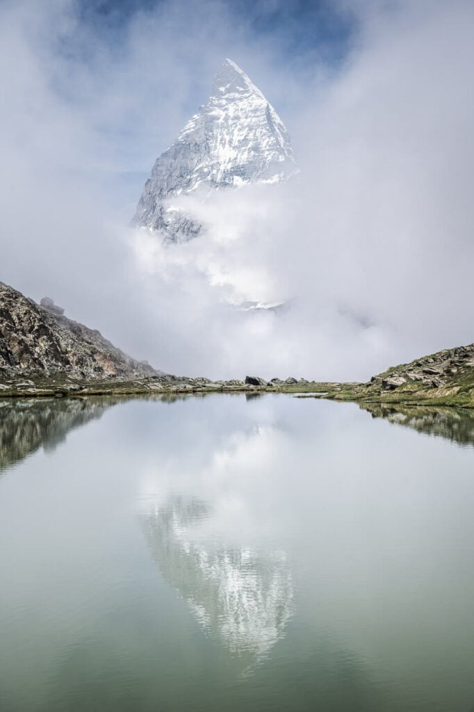 Matterhorn is surrounded by clouds and the Riffelsee, one of the ironing hiking and photography locations in Switzerland.