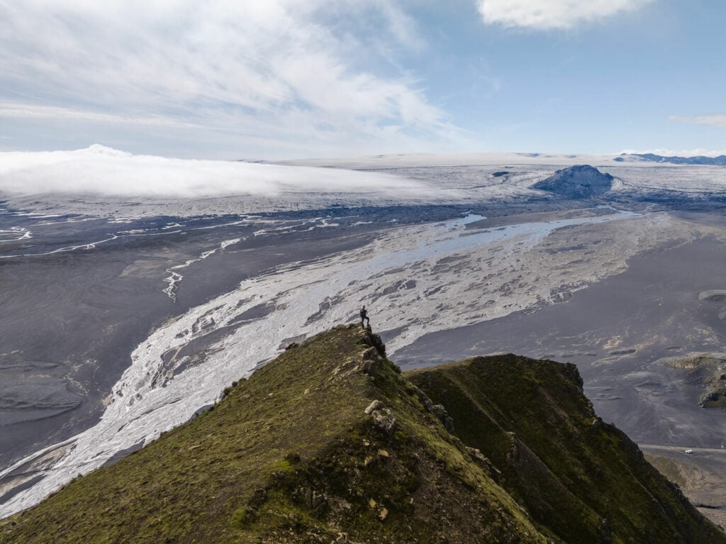 Hiker on top of the Mælifell volcano with the Mýrdalsjökull glacier in the background