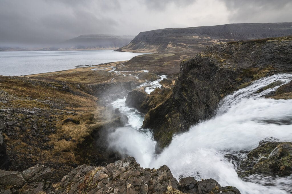 View of fjord and a waterfall on a cloudy, rainy day.