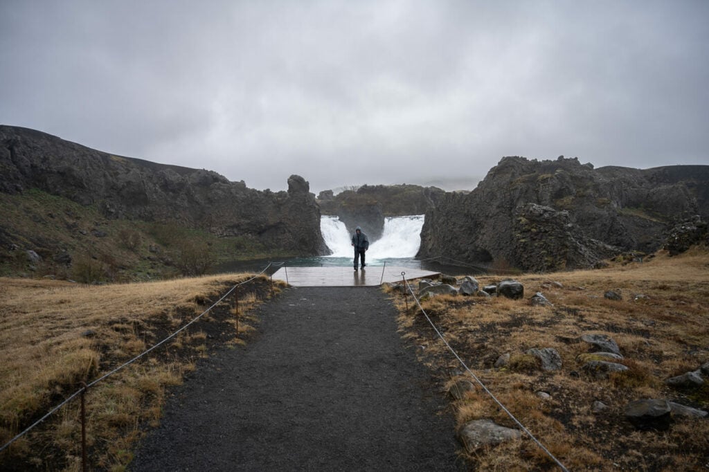 Hjalparfoss on a rainy day with a passerby.