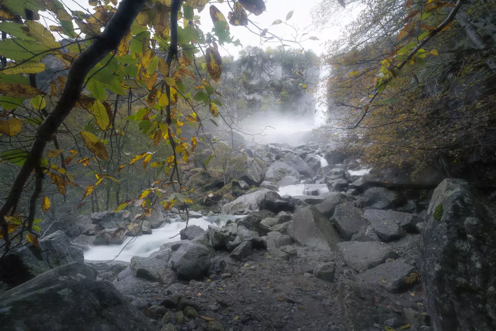 Cascata di Foroglio with some rocks in the foreground and colorful autumn leaves