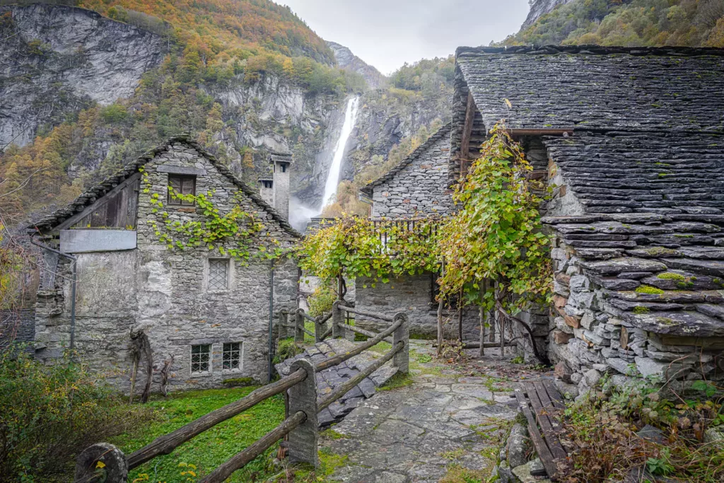 The Forogio waterfall viewed from the Village of Foroglio, in between stone houses.