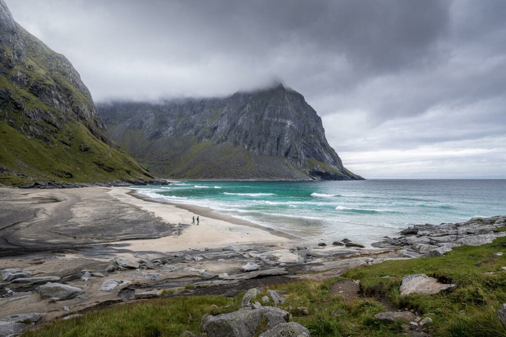 Kvalvika beach with two people walking by on a cloudy day