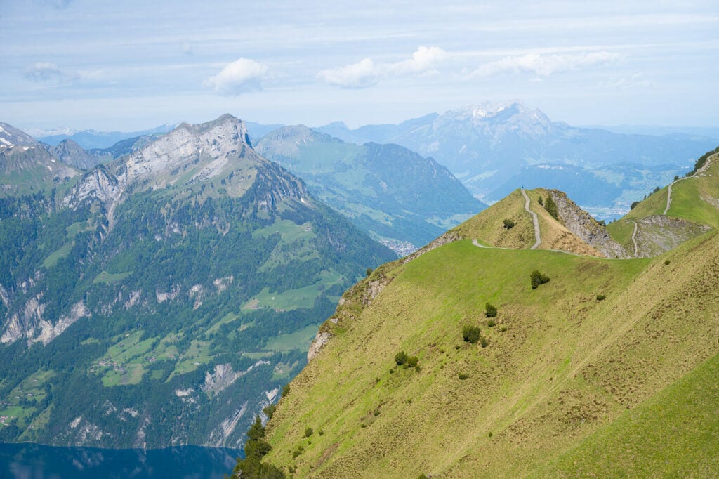 Panoramic view from a ridge trail in Switzerland with several mountains in the background.