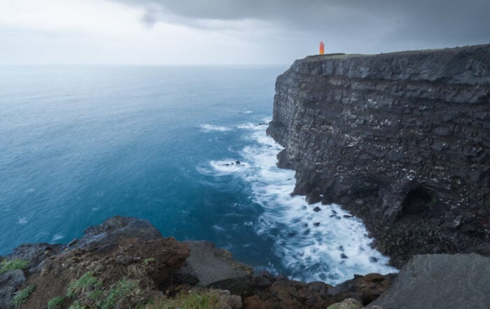 View of the Krisuvikurberg cliffs and the orange lighthouse on top of them