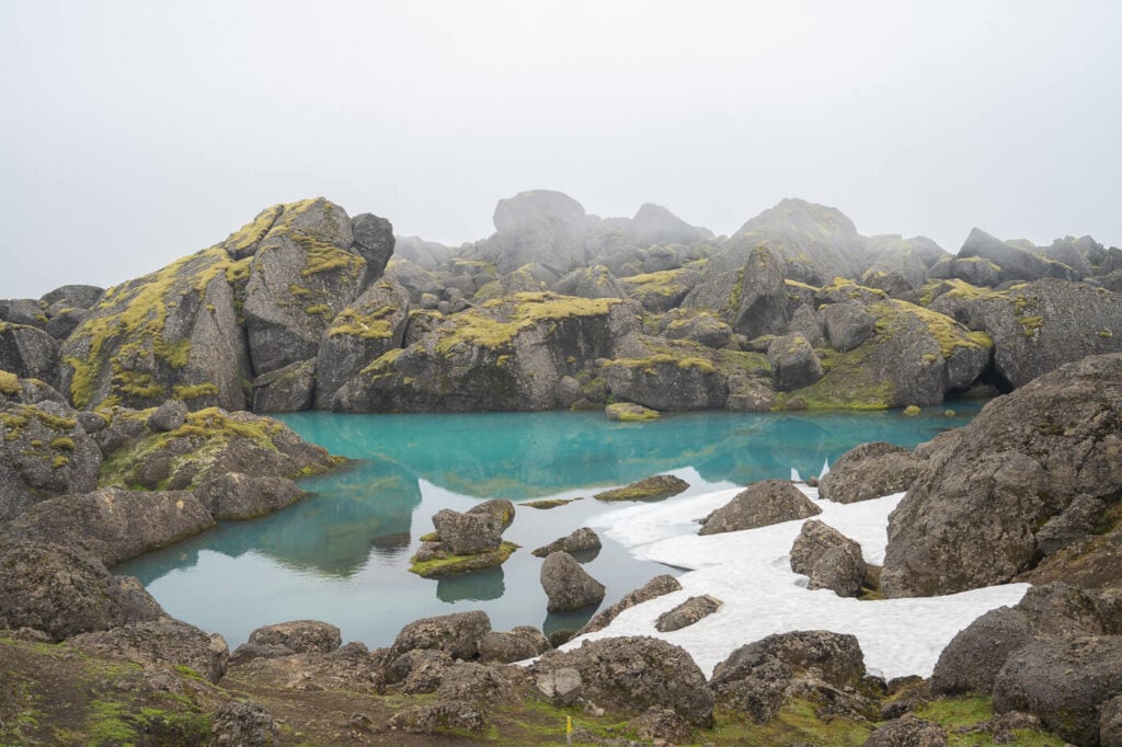 Stórurð lake with snow and ice in it on a foggy day.