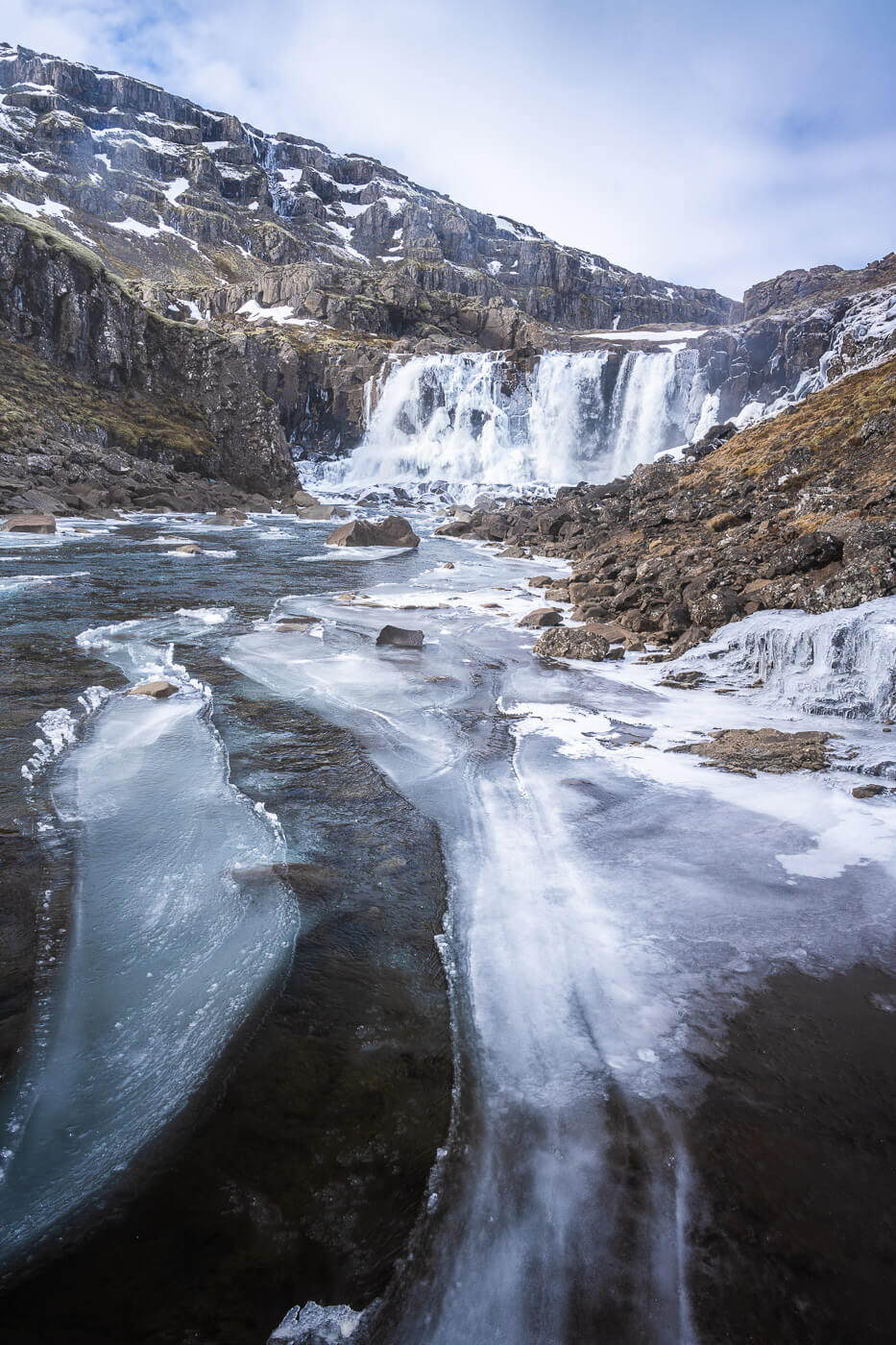 Partially frozen waterfall in iceland that can only be reached when hiking