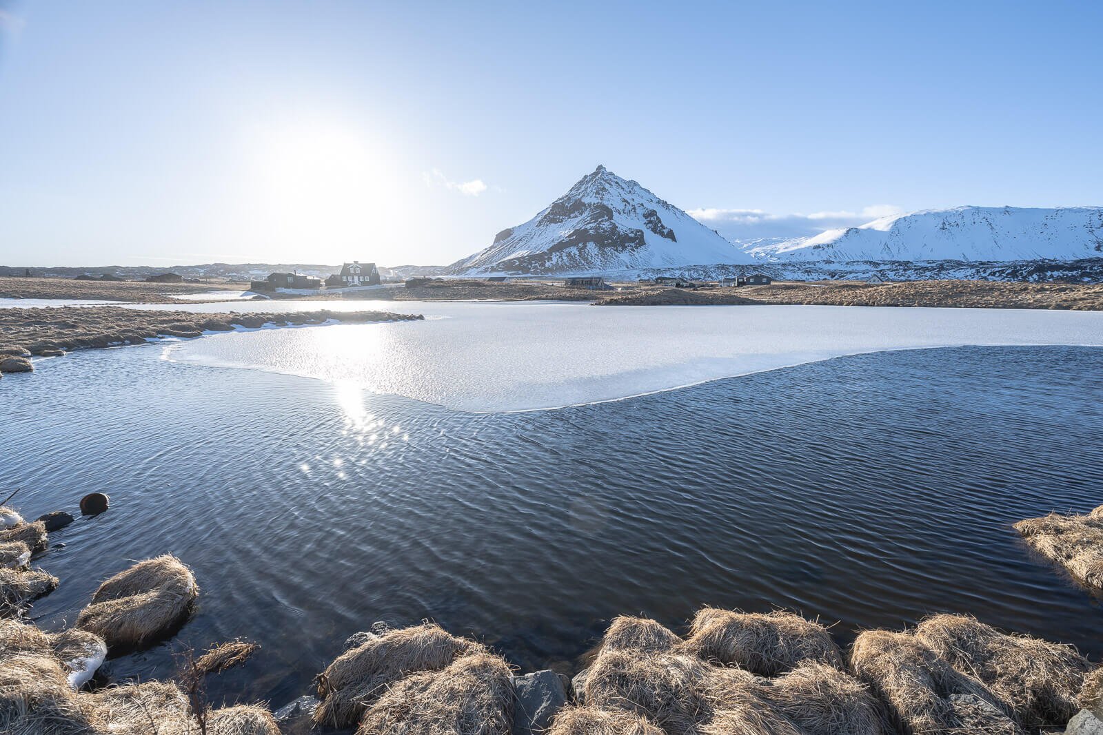 Winter landscape in Iceland in March, with a partially frozen lake on the Arnarstapi coastal hiking trail.