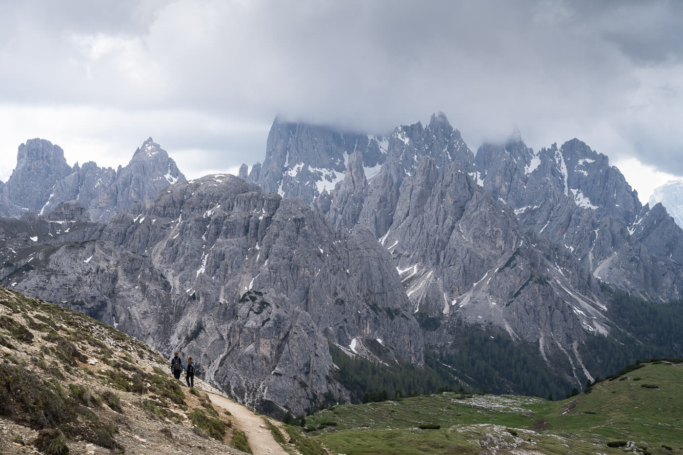 HIkers on a hike in the dolomites, with jagged mountains in the background.