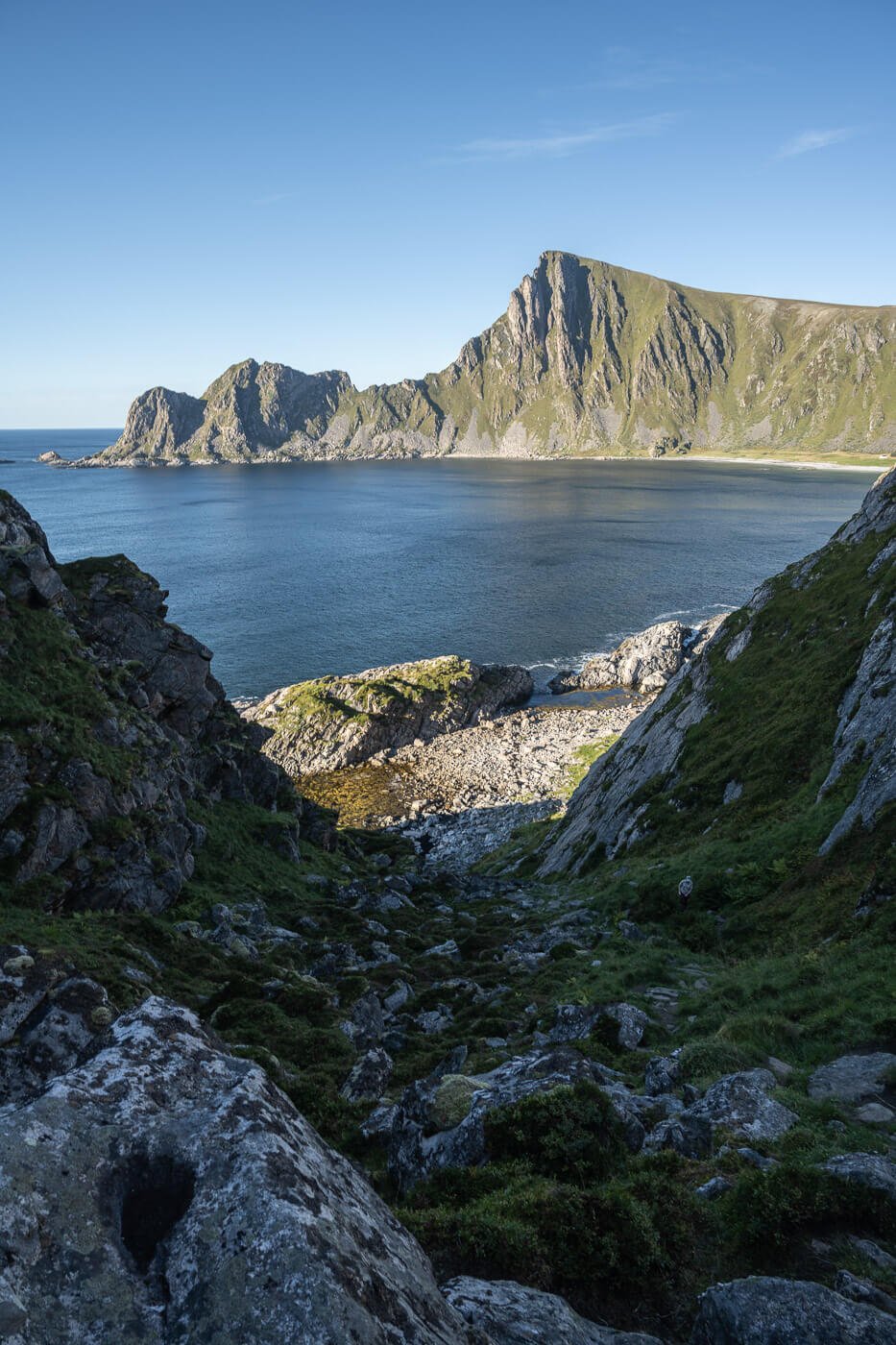 View of a rocky shore with steep mountains around it.