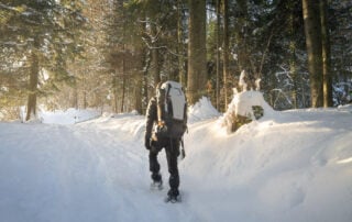 Hiker on snow with the Lowepro Photosport Pro 70l aw iii camera backpack