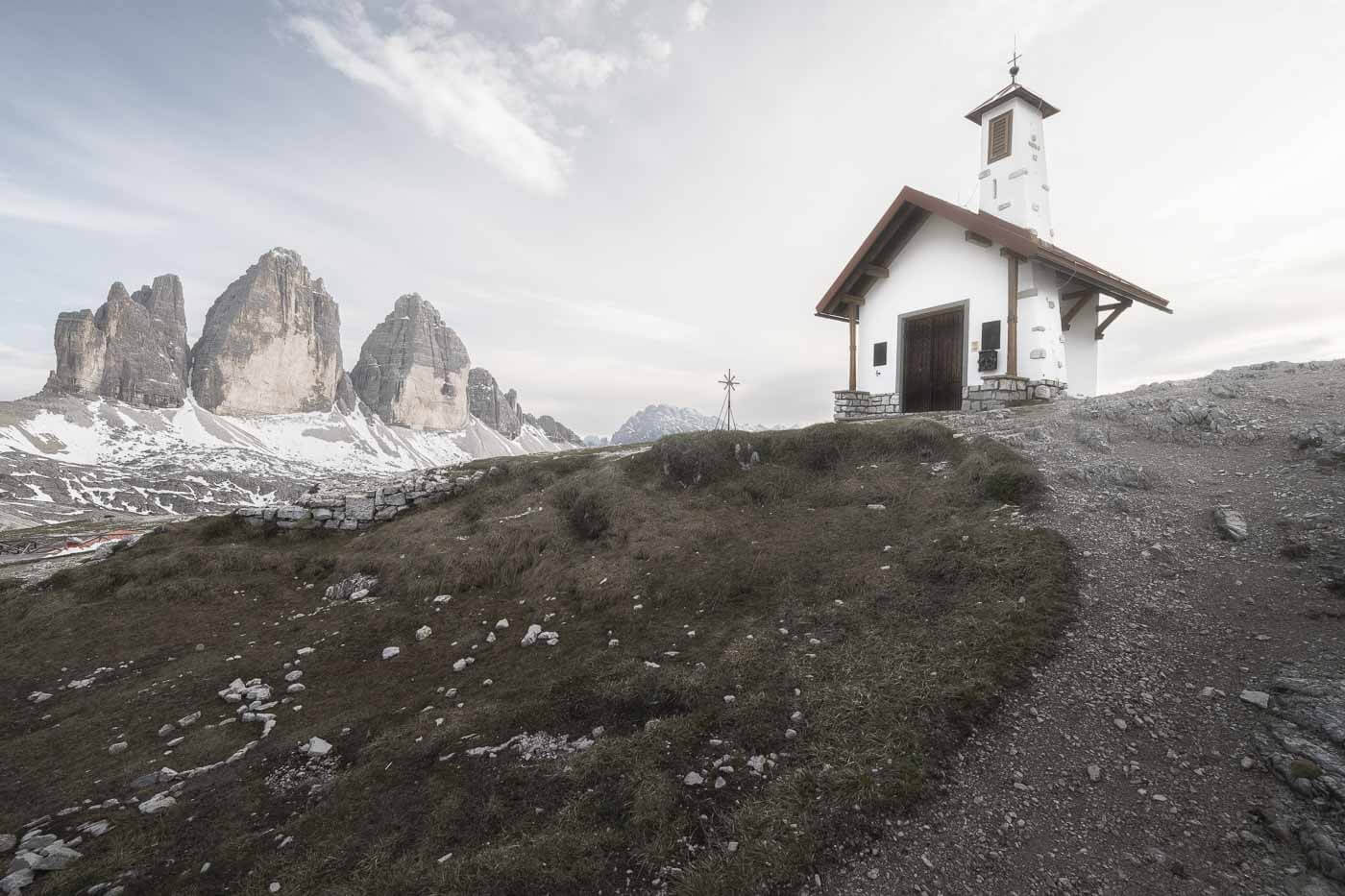 View of a small chapel with Le Tre Cime di Lavaredo in the background.