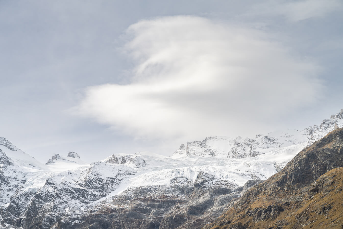 Details of glaciers in the gran paradiso national park, with a lenticular could above them.