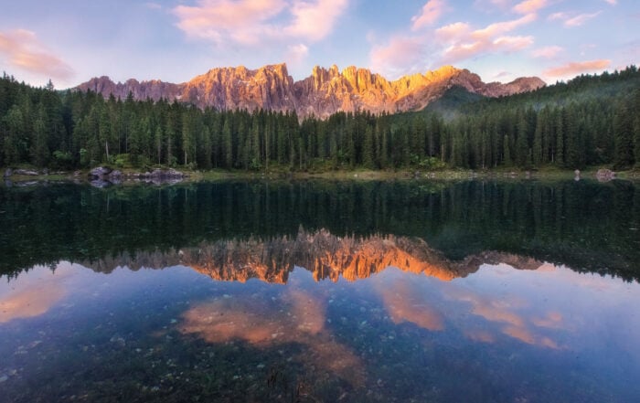 Sunrise at Lago di Carezza, with the warm morning light lighting the mountains.