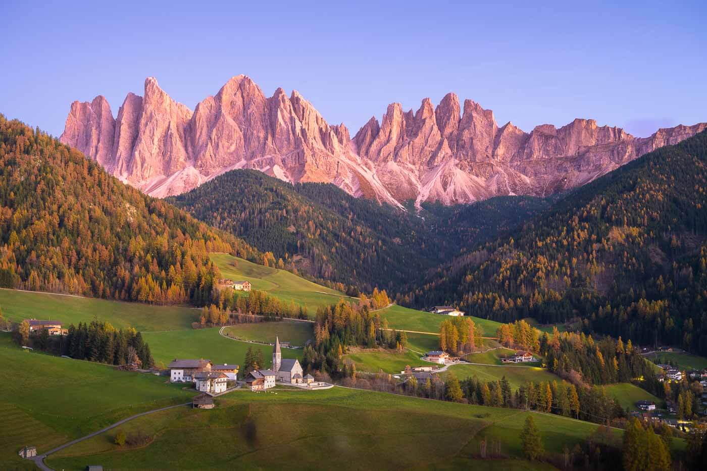 Vide of the Odle group in Villnöß valley in the Dolomites after sunset, with pink colors on the mountains.