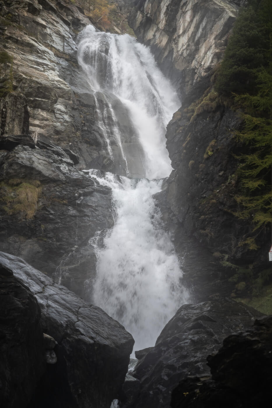 Powerful waterfall nestled between the rocks, with a lot of water spray around it