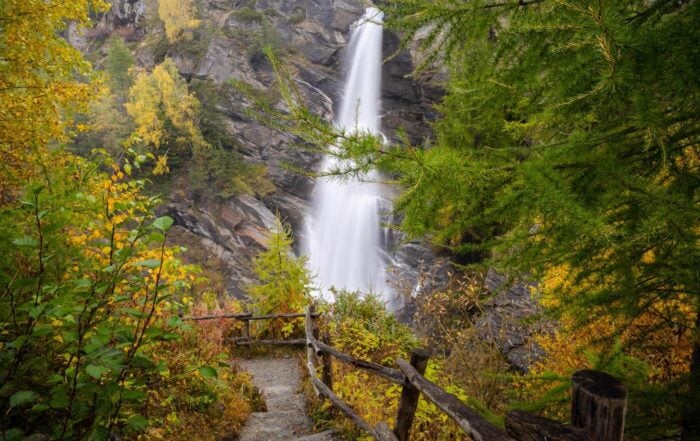 VIew of one of le Cascate di Lillaz surrounded by foliage in fall colors.