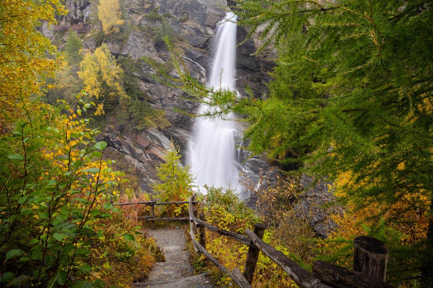 VIew of one of le Cascate di Lillaz surrounded by foliage in fall colors.