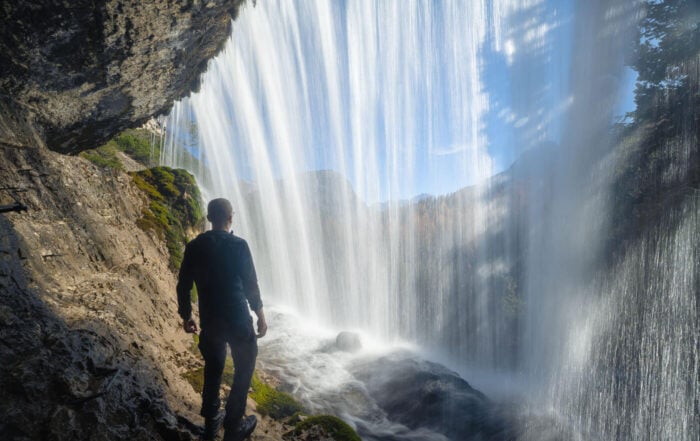 Hiker behind a waterfall of Cascated di Fanes in the Dolomites