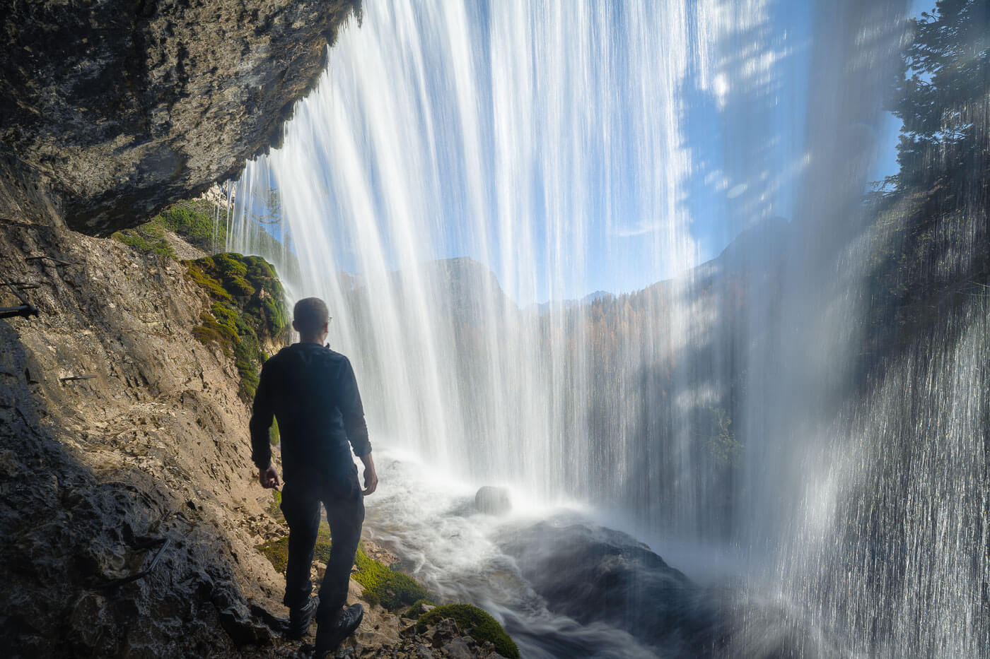 Hiker behind a waterfall of Cascated di Fanes in the Dolomites