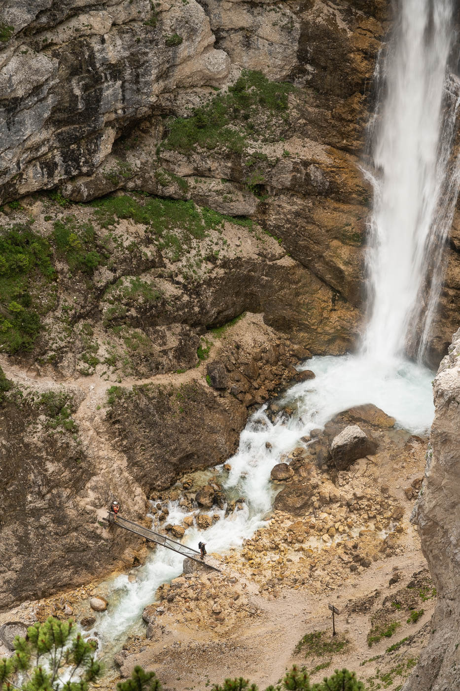 Via ferrata at Cascate di Fanes with people below the waterfall.