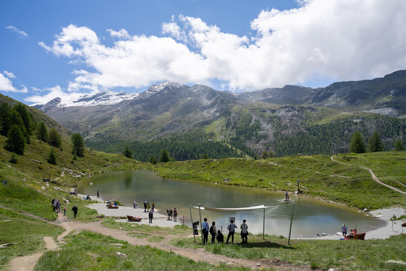 Hikers enjoying the landscape on the shores of Leisee, a mountain lake on the Five Lakes trail in Zermatt.