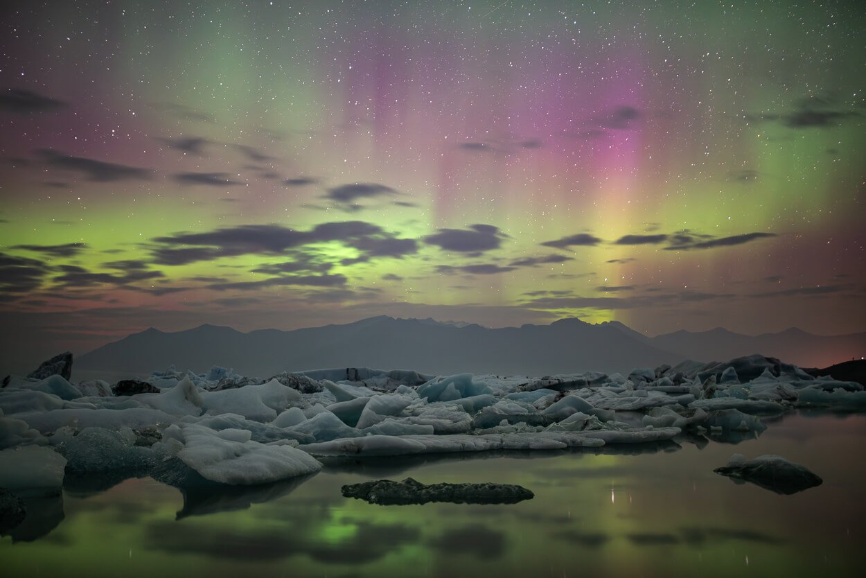 Northern lights at the iceberg lagoon in Iceland, with colored aurora above the ice.