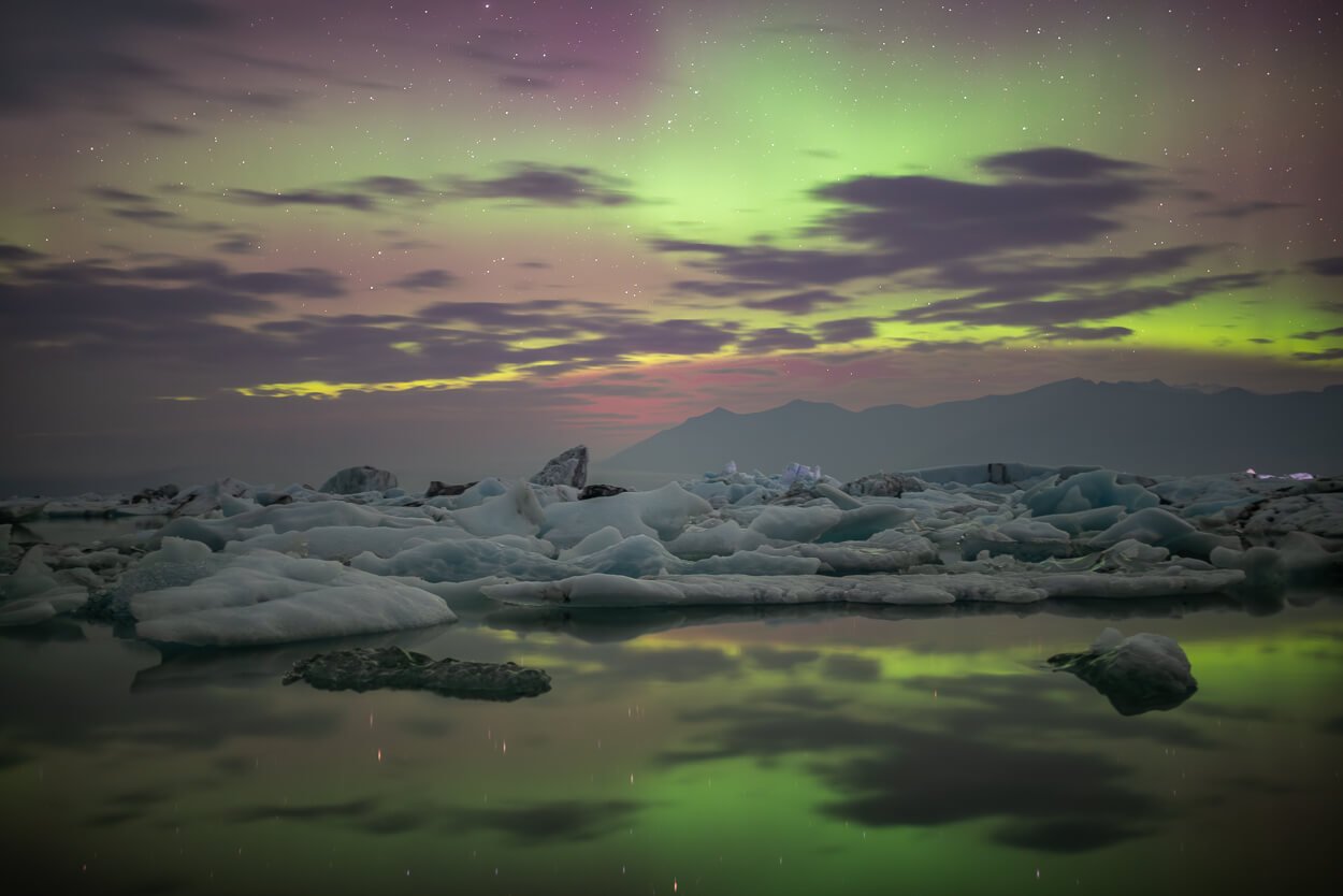 Northern lights at Jokulsarlon in Iceland, with icebergs floating.