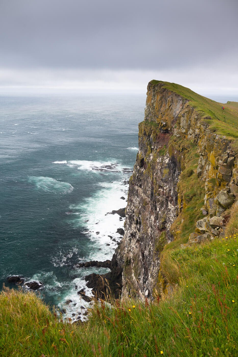 Vertical image of a steep drop from a sea cliff.