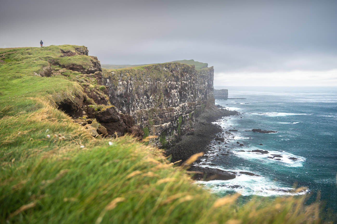 Hiker on the Látrabjarg cliffs on a cloudy day.