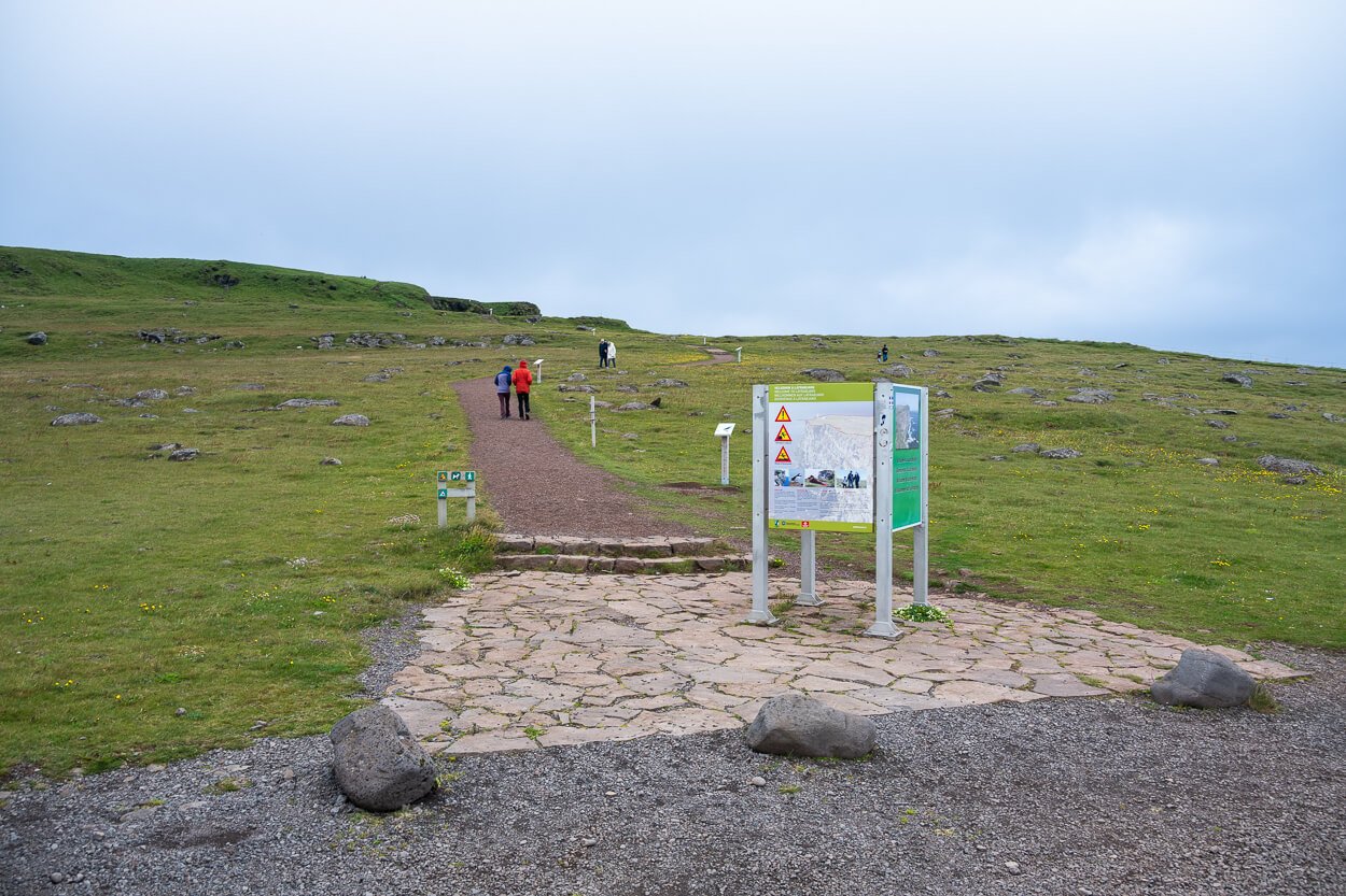 Látrabjarg trailhead and infoboard with hikers in the background.