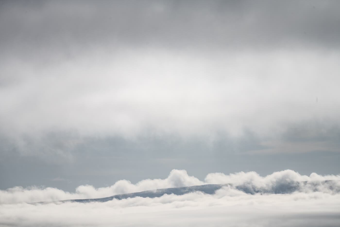 clouds with a small limb of a hill peeking through.