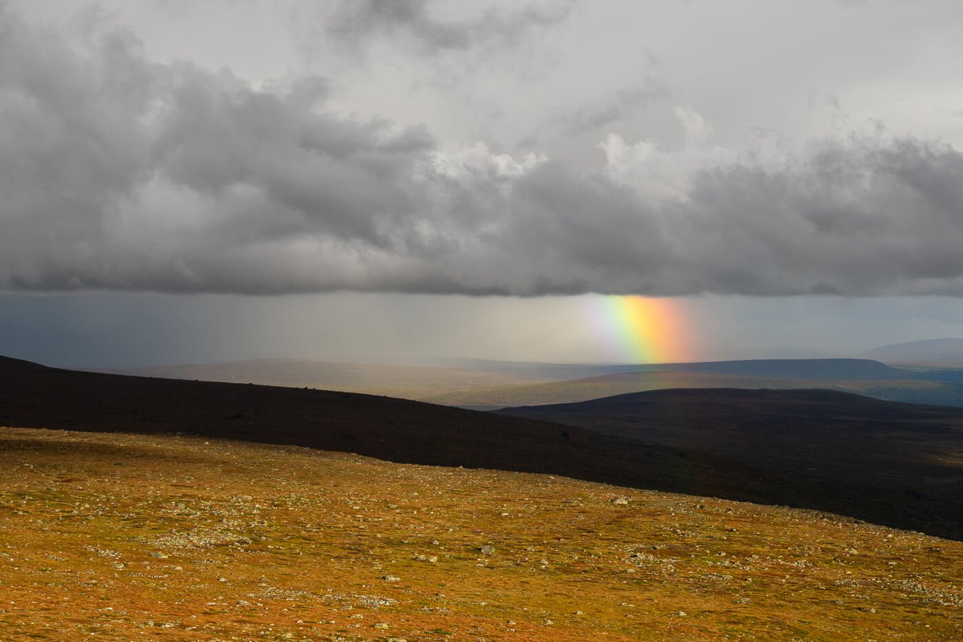 Rainbow, rain, and clouds in an autumn scenery in the Arctic.