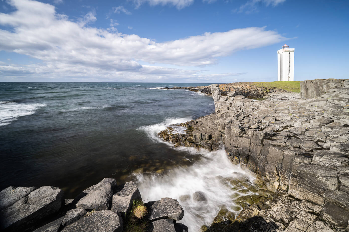 Shoreline with a lighthouse in north iceland wad waves crashing against the rocks