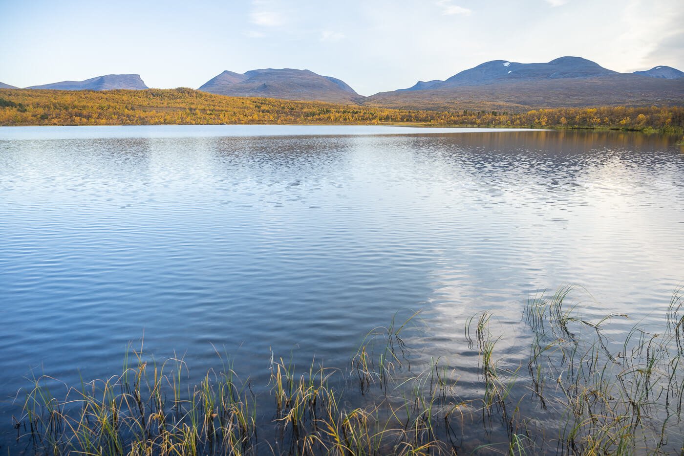 Lake Njakajaure with calm waters and the moutains of Swedish Lapland in the background