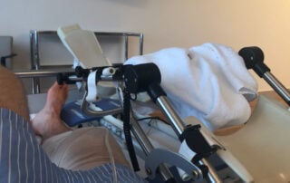 Post ACl Surgery Patient on a hospital bed with a CPM machine next to the bed