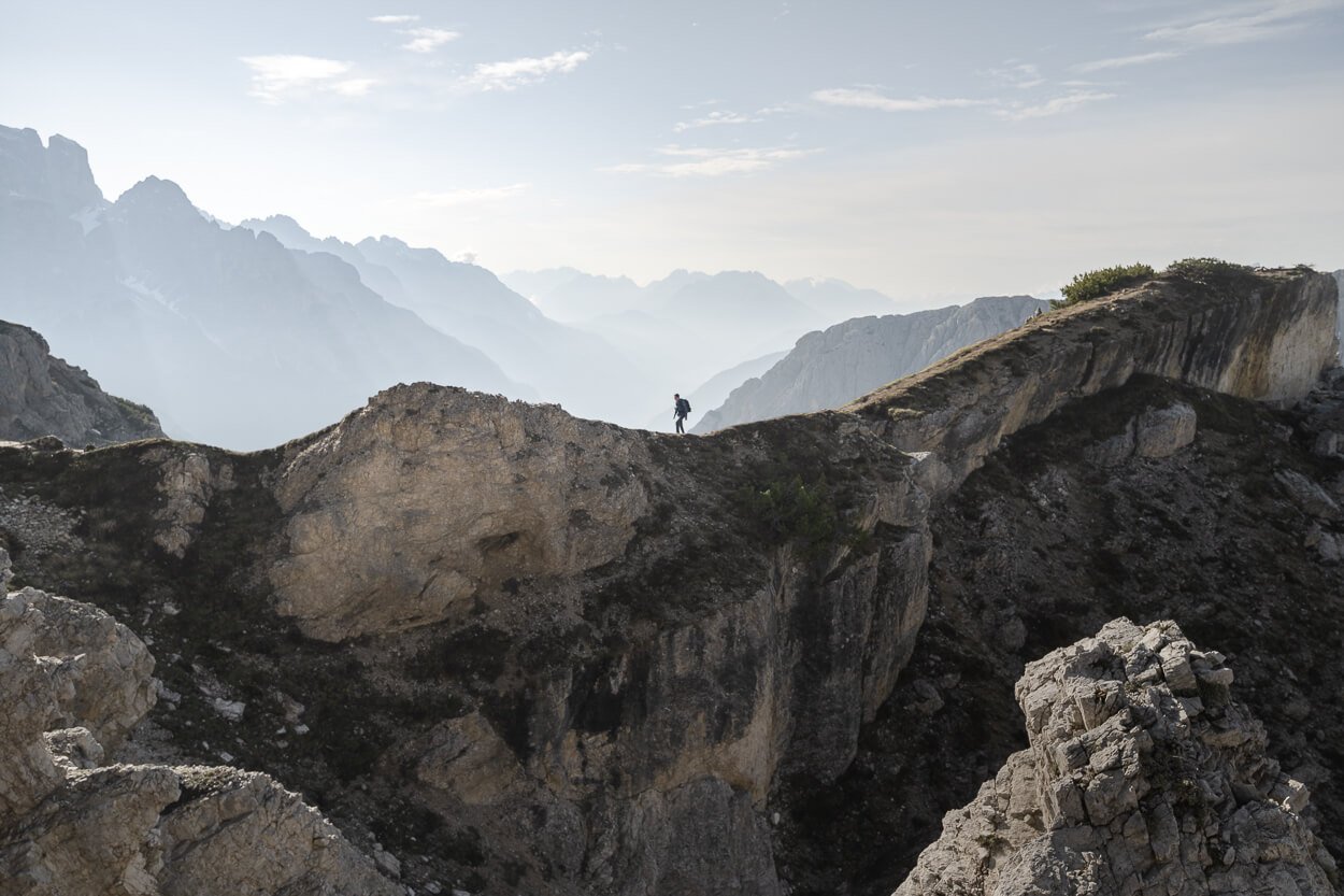 Hiker walking on a ridge to get to the Cadini di Misurina viewpoint.