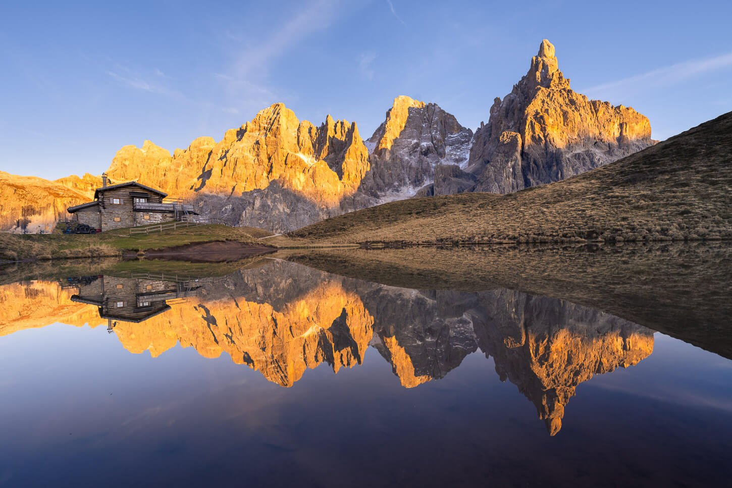View of the Pale di San Martino reflectin in the lake next to Baita Segantini at Sunse, for one of the Best Sunset hikes and photo posts in the Dolomites.