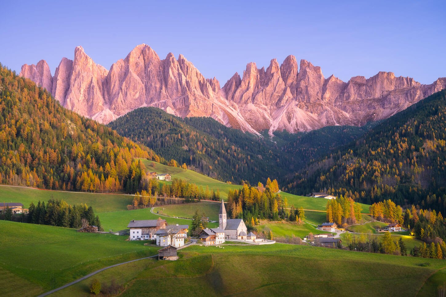 View of the Church in Val di Funes with the Dolomites catching the Alpenglow, one of the best photo spots in the Dolomites.