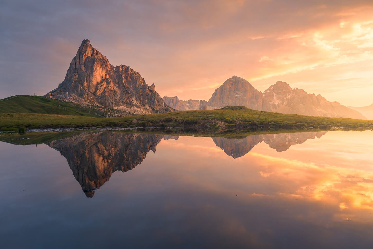 Landscape photography image of mountains reflecting in a lake at sunrise in the Dolomites.