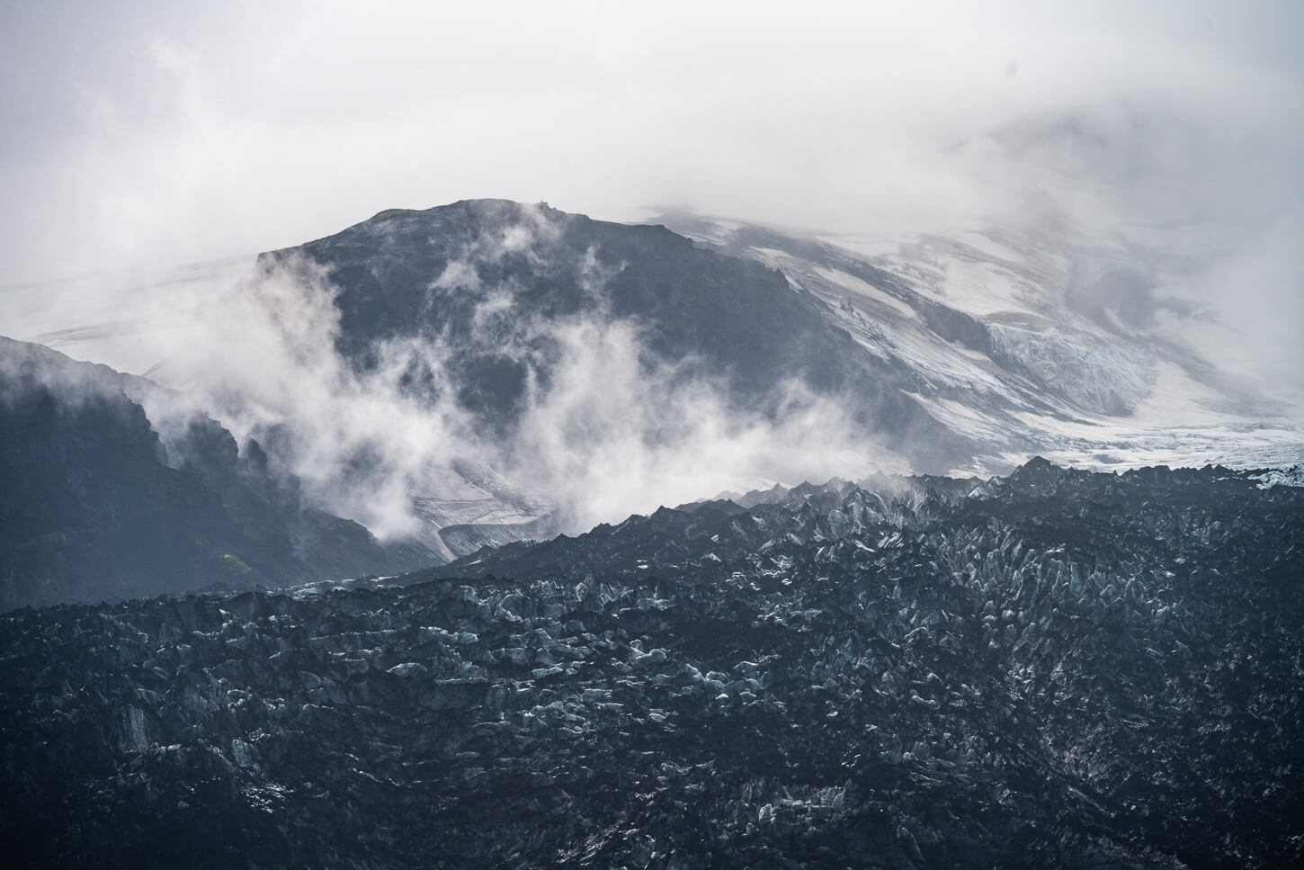 Details of am ash covered glacier in the mist between the clouds.