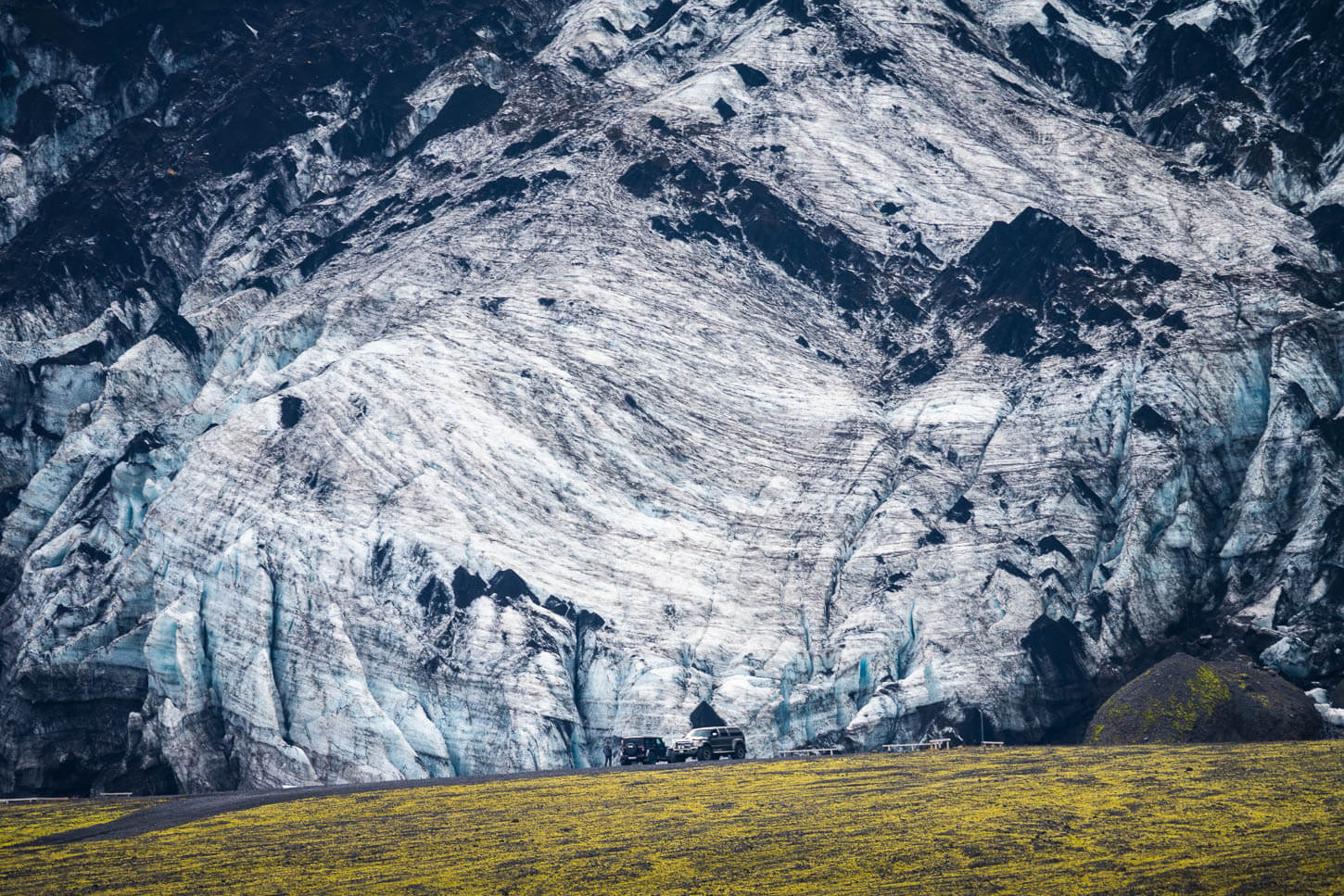 Detail of the Gígjökul glaciers from a distance with large 4WD vehicles in front of it