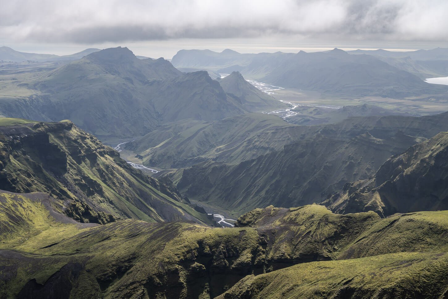 view of green valleys and rivers that can be visited on a hike in Þakgil