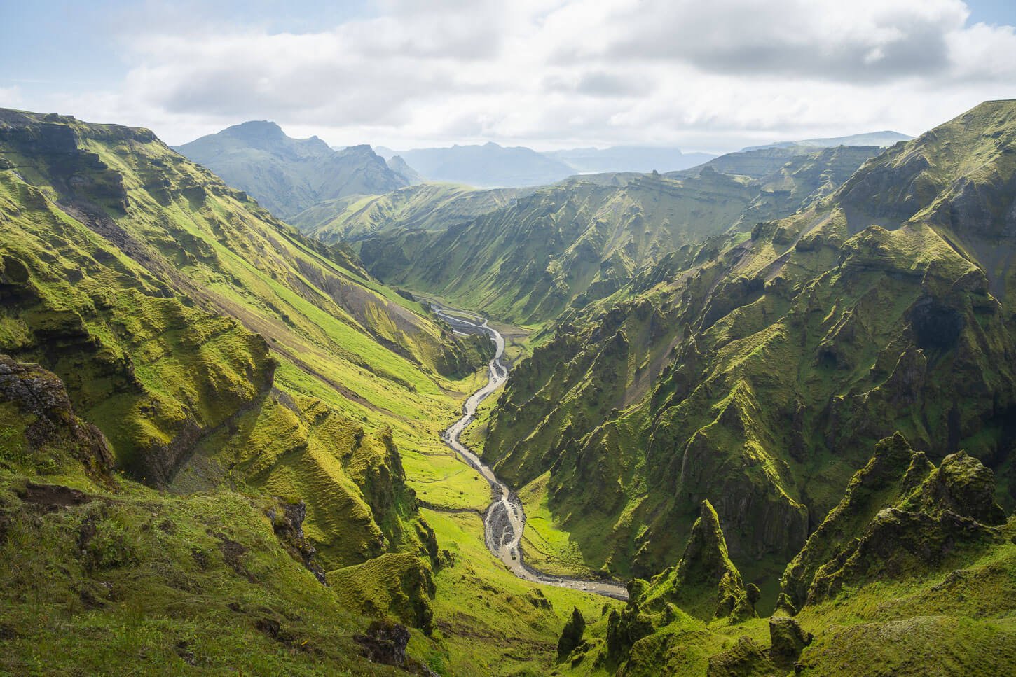 View of a green lush ravine with a river at the bottom of it in Thakgil