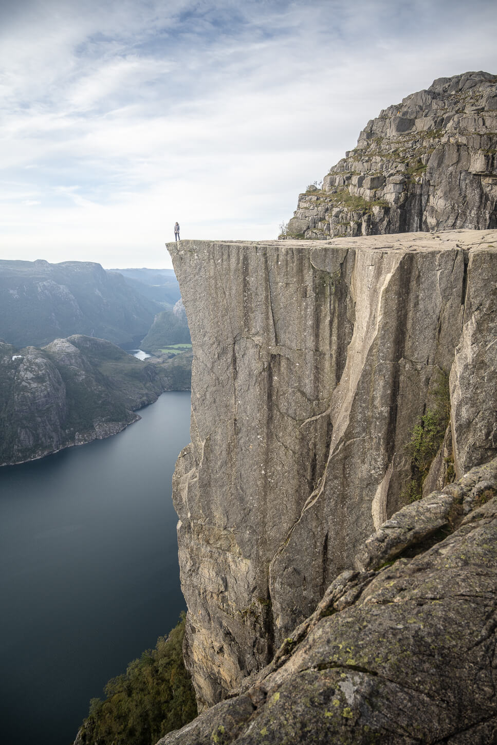 Landscape photo of preikestolen with a human figure representing the human element to give a sense of scale of the place.