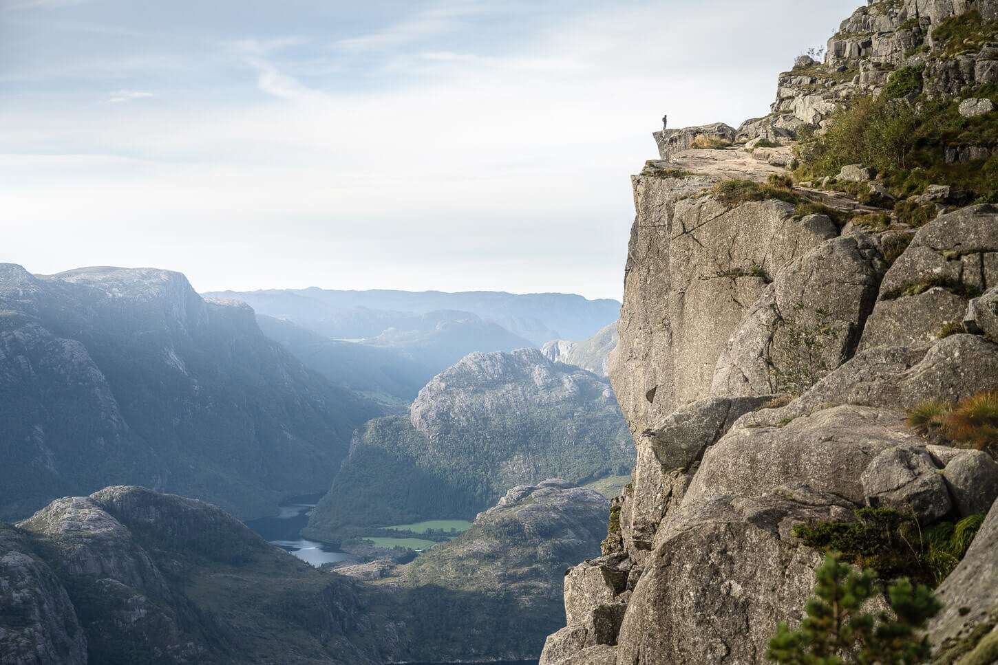 Hiker standing alone on the top of the Pulpit rock or Preikestolen in Norway.
