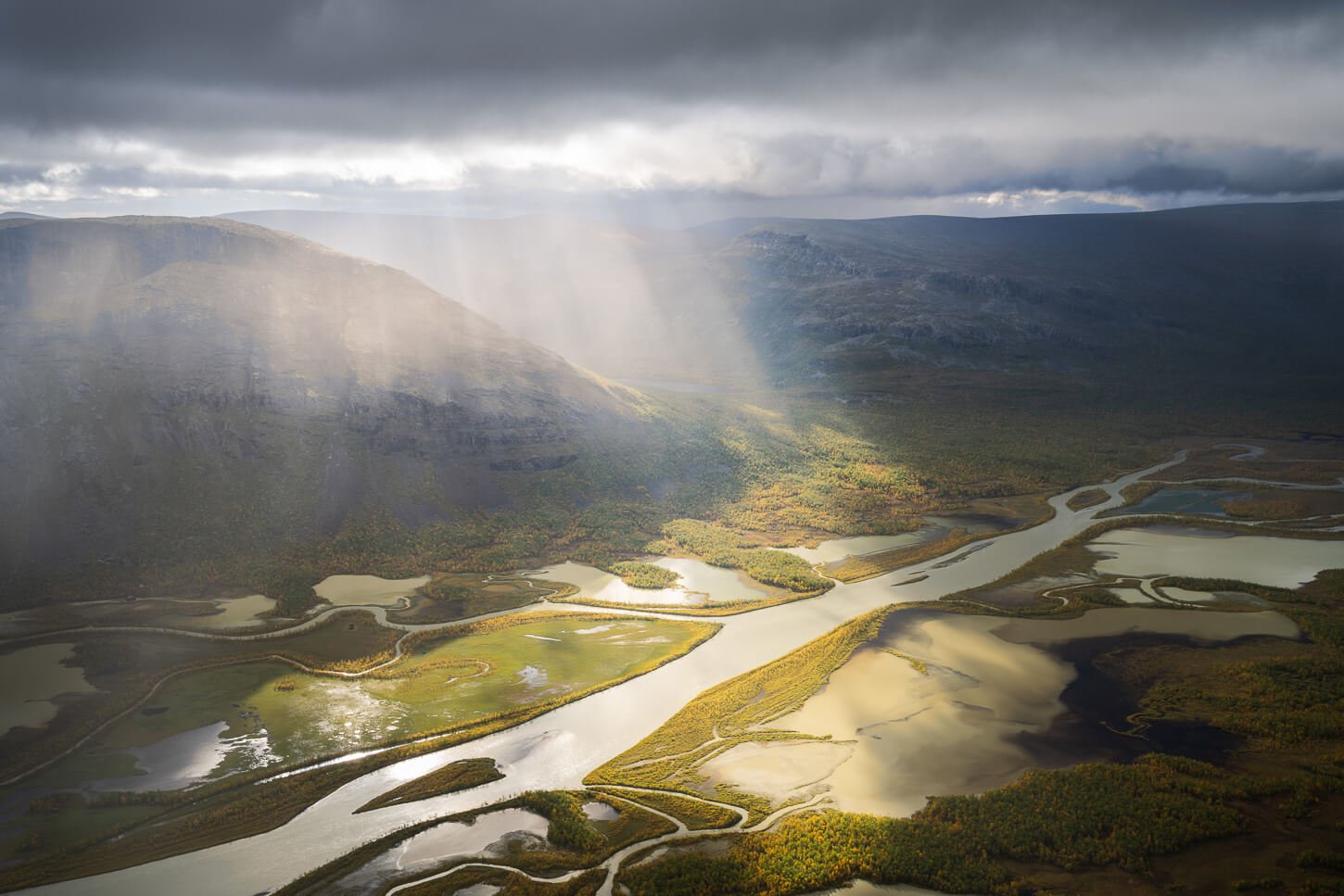 Dramatic light passing thrugh a break in the clouds above the meandering Rapa river delta in Swedish Lapland